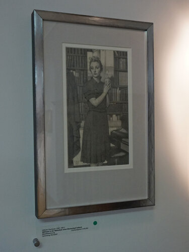 Wilfrieda in der Bibliothek einen Blumentopf haltend